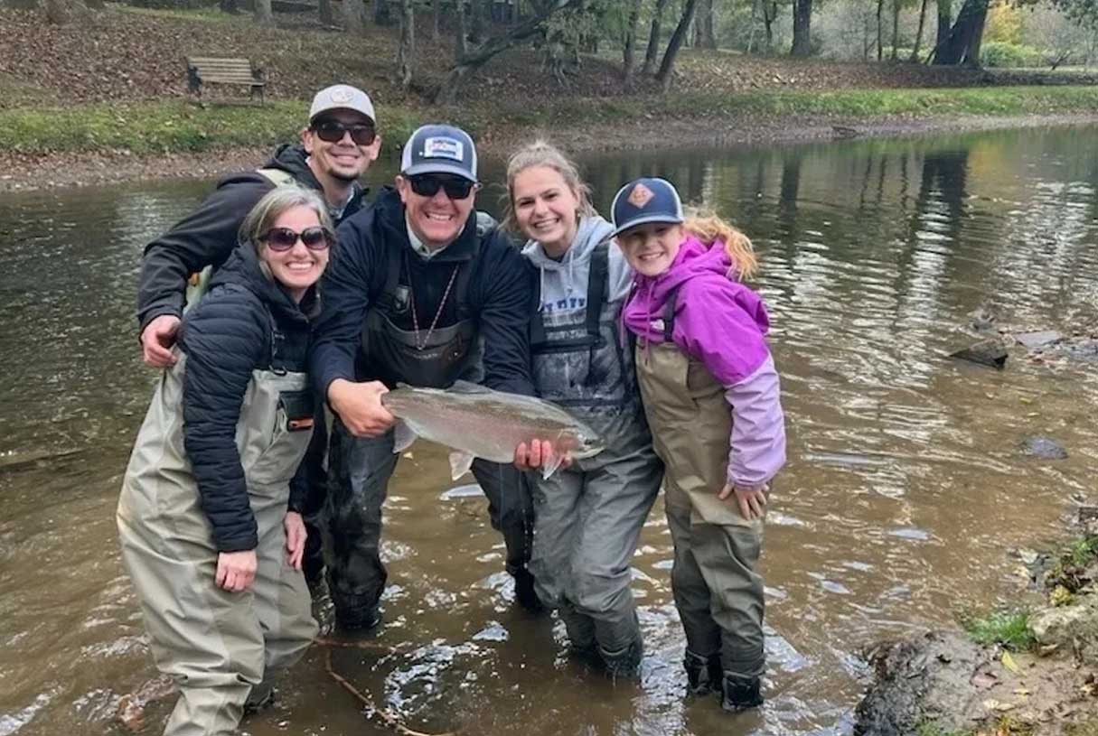 Photo of a family holding a trout they caught while fly fishing on a stream in north Georgia.